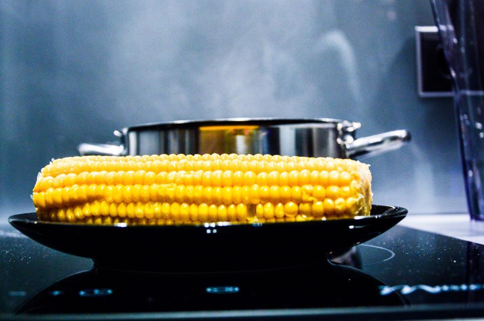 Free Image of Steaming pot with corn on the cob on black plate. 