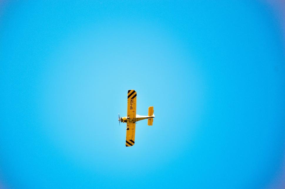 Free Image of Yellow airplane soaring in clear blue sky. 