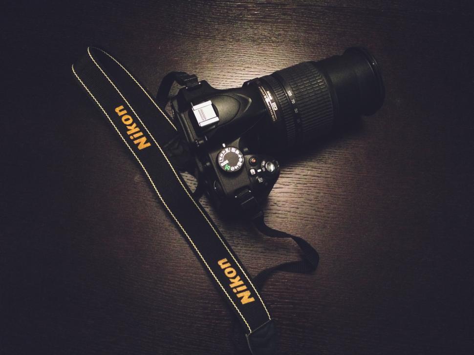Free Image of Black Nikon DSLR camera with telephoto lens on table. 
