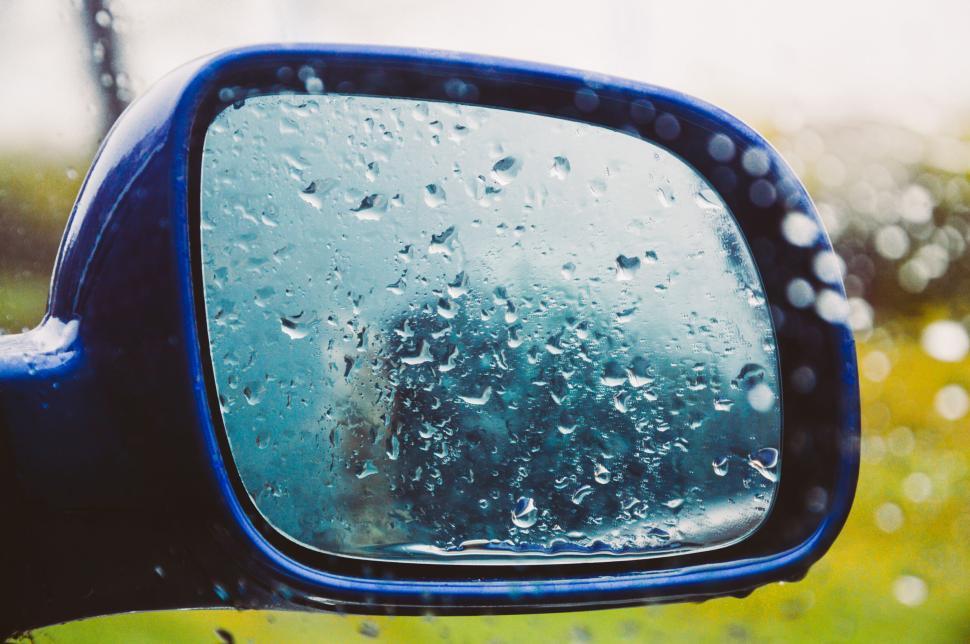 Free Image of Car side mirror with raindrops and blurred background. 