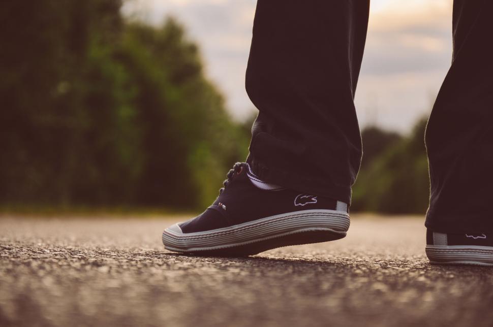 Free Image of Close-up of sneakers on pavement with nature background 