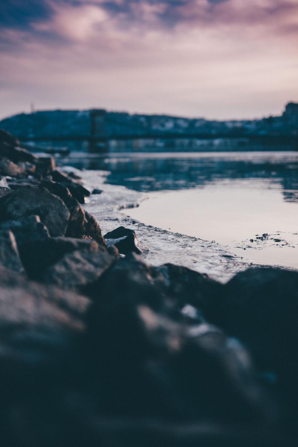 Free Image of Rocky shoreline with calm waters at sunset time 