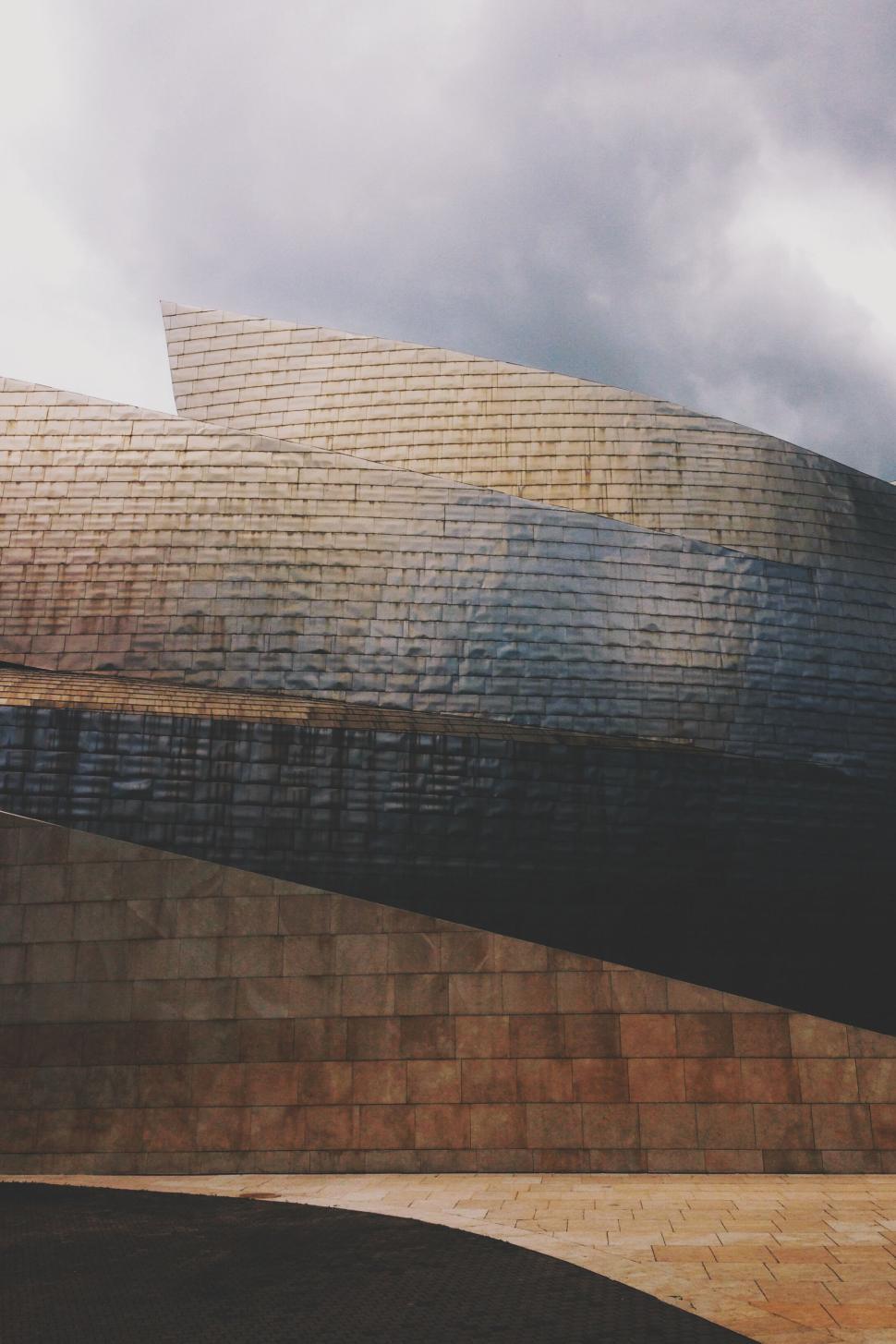 Free Image of Curved metallic building facade under cloudy sky. 