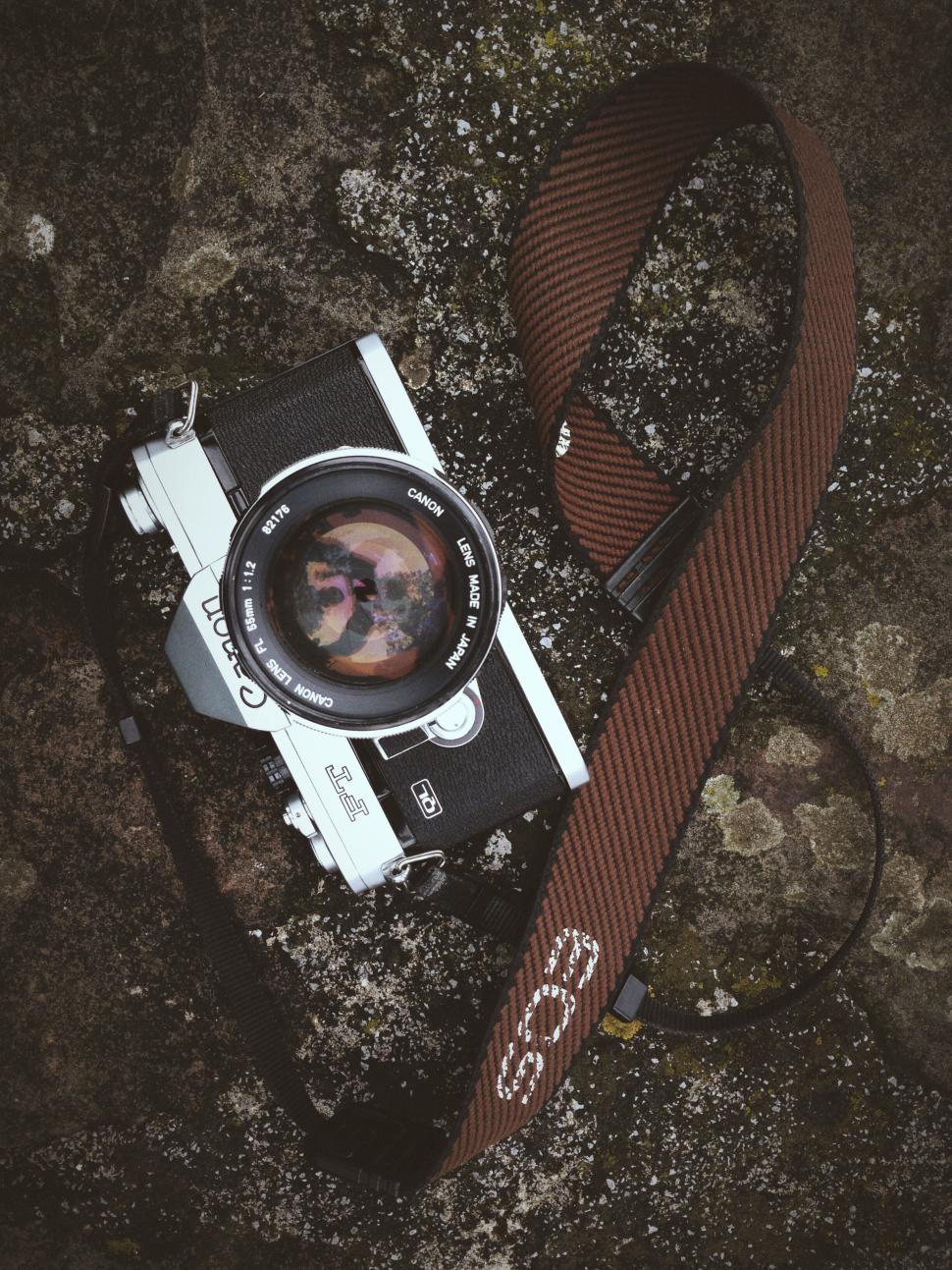 Free Image of Vintage film camera with strap on textured surface. 