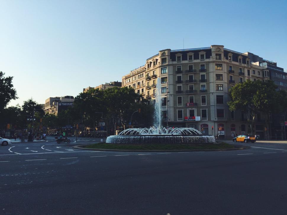Free Image of Fountain in a city square with surrounding buildings 