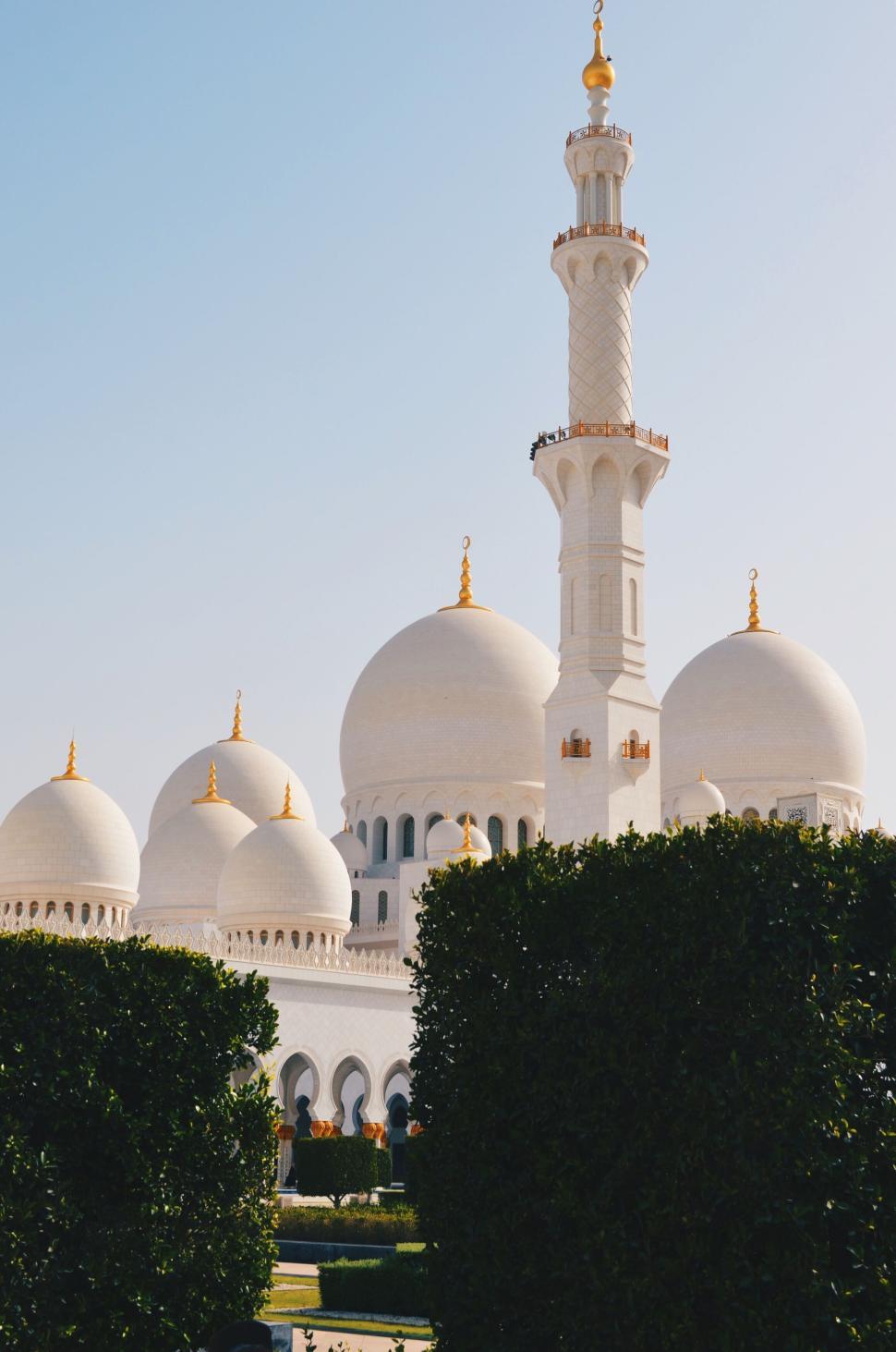 Free Image of White mosque with minarets surrounded by green bushes 