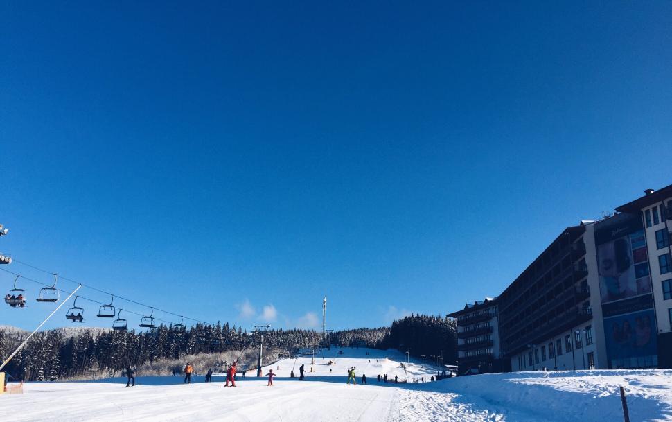 Free Image of Snow-covered ski slope with skiers and chair lifts visible 