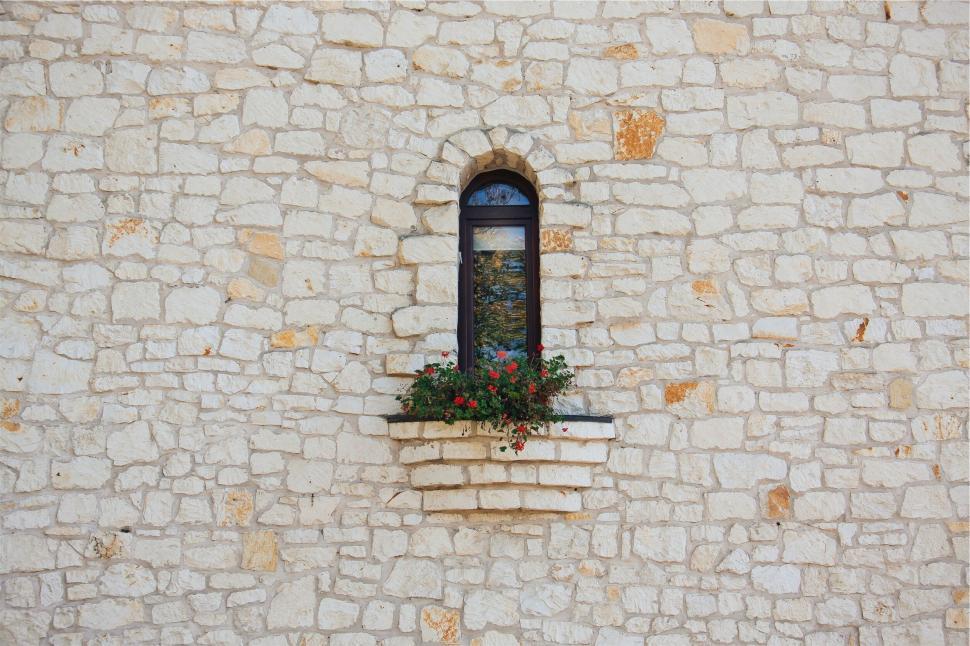 Free Image of Stone wall with a window and flower box with red flowers 