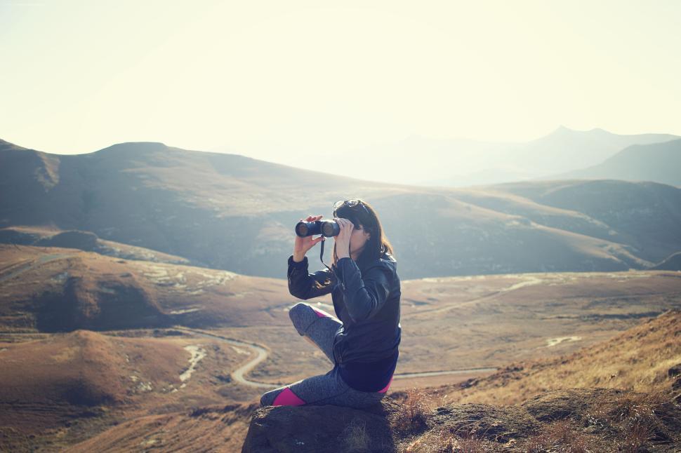 Free Image of Person with binoculars sitting on a mountain slope 