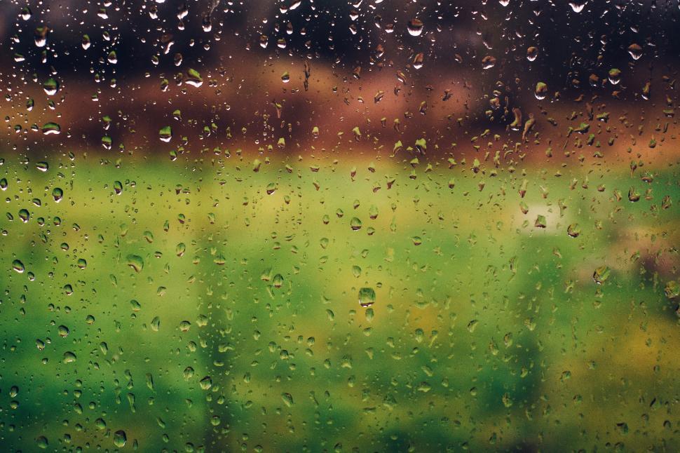 Free Image of Raindrops on a window with blurry green field view. 