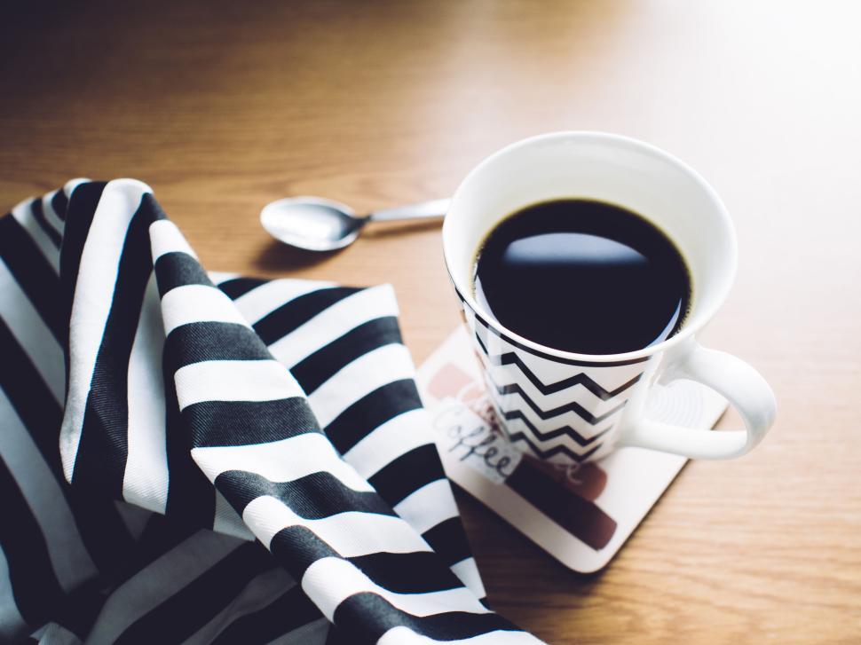 Free Image of A cup of black coffee with a striped napkin nearby. 