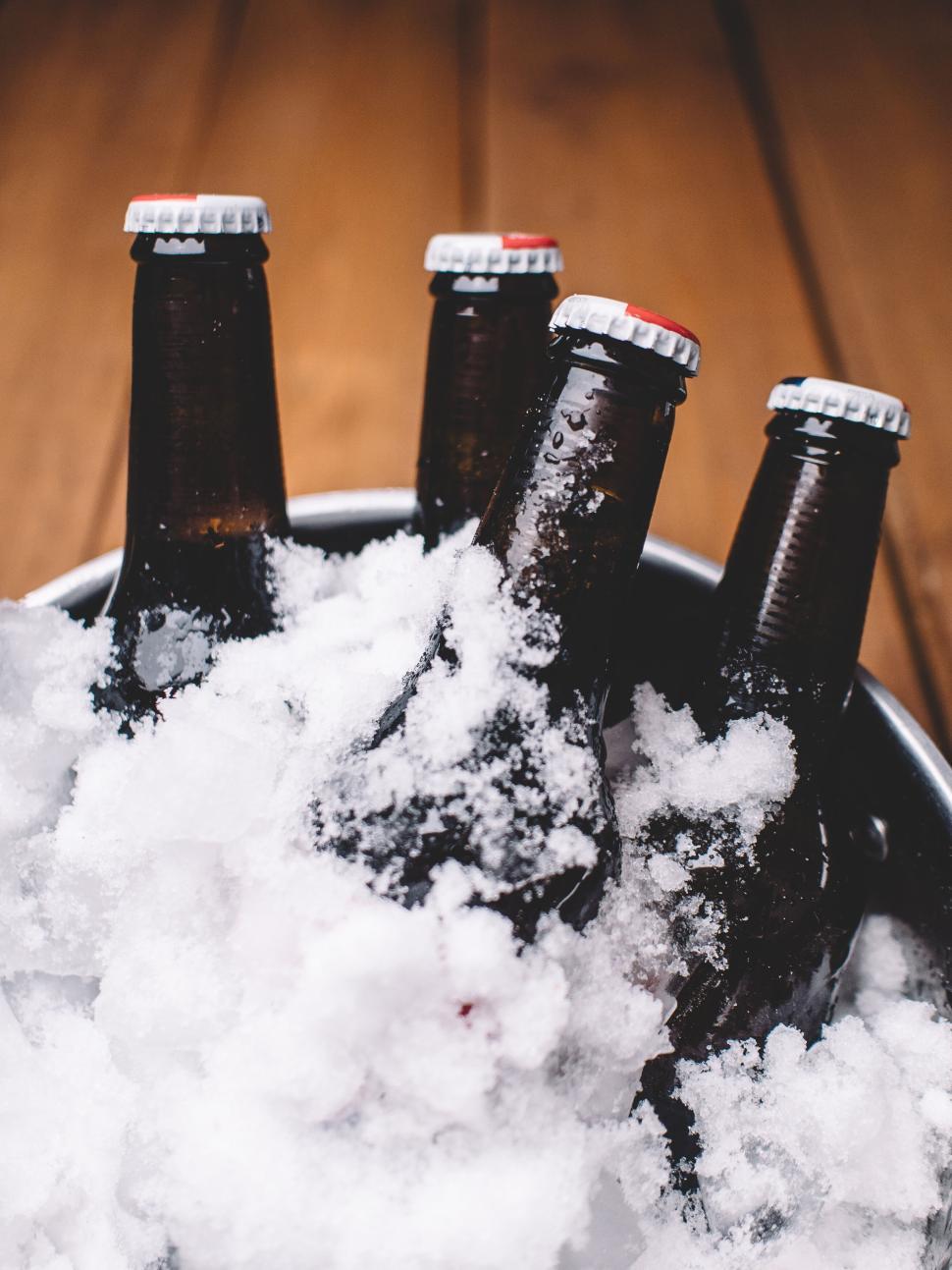 Free Image of Five bottles of beer with caps, chilled in icy snow, perspective 