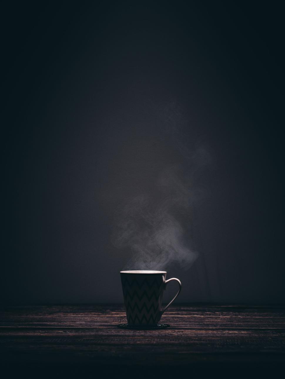 Free Image of Steam rising from a black coffee mug on wooden table 