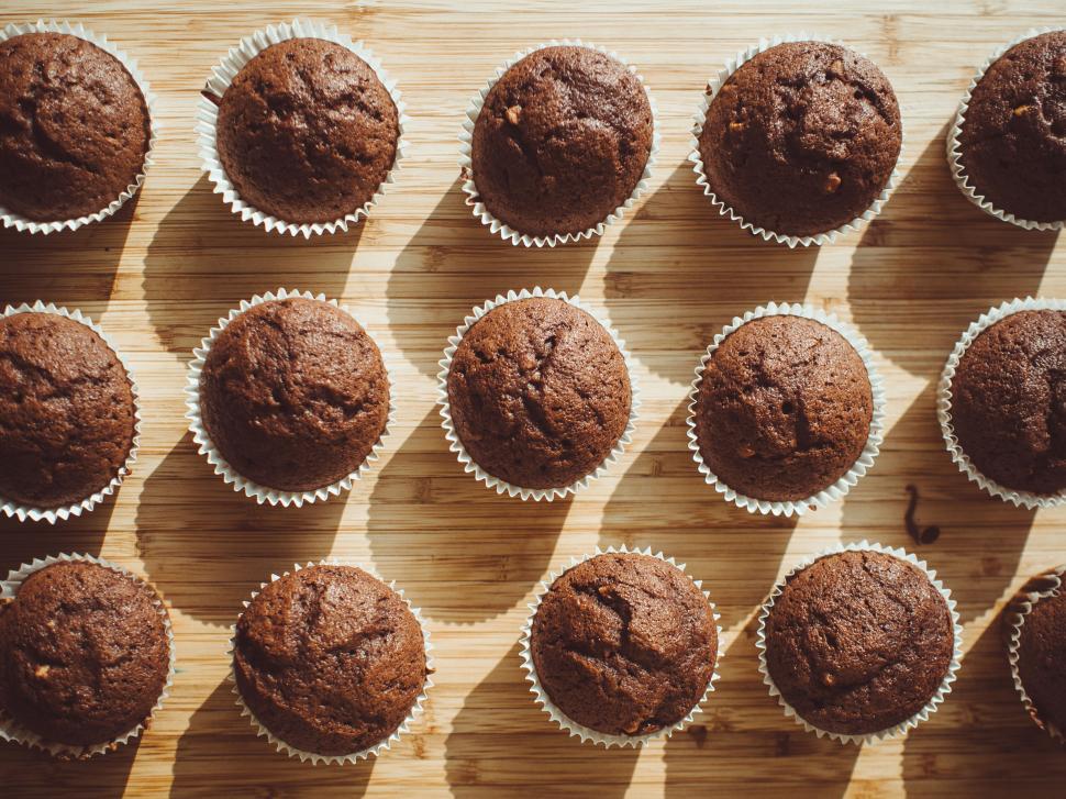 Free Image of Chocolate muffins arranged on a wooden surface in rows. 