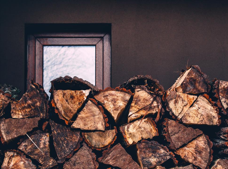 Free Image of Stacked firewood in front of a small window frame 