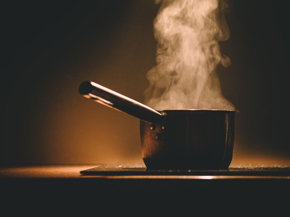 Free Image of Steam rising from a saucepan on a lit stove top. 