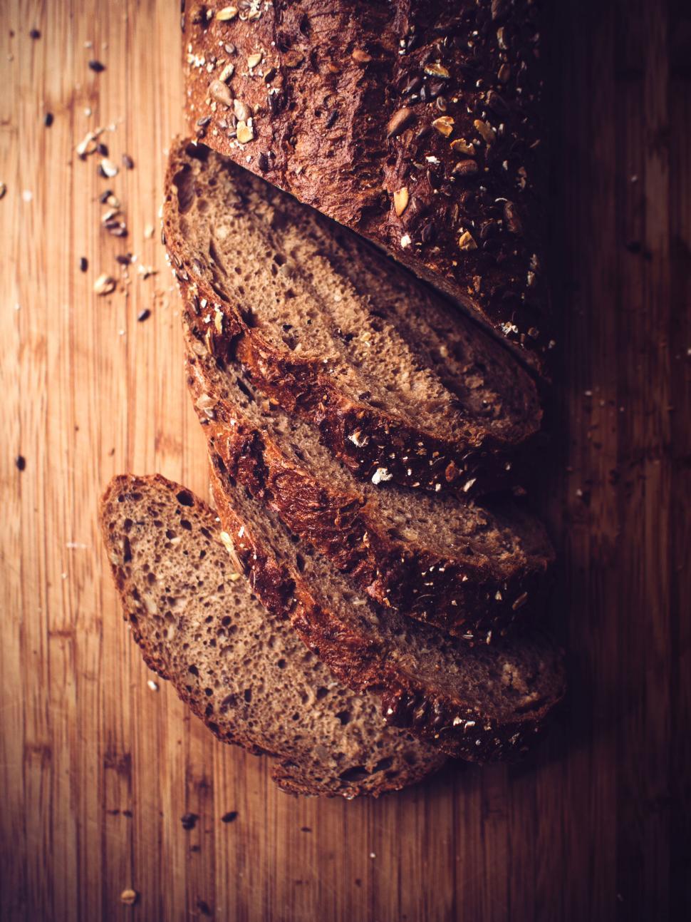 Free Image of Loaf of bread with three slices on wooden surface 