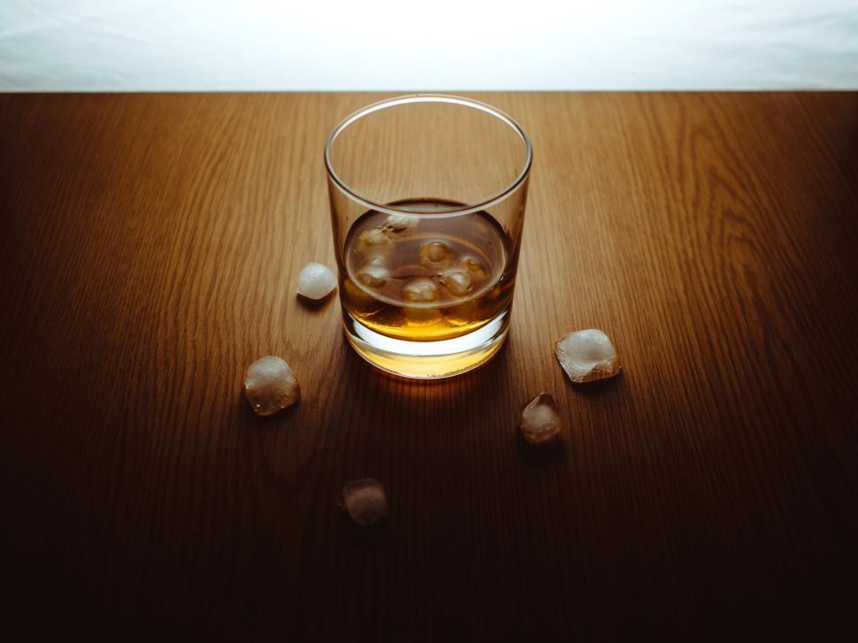Free Image of Glass of whiskey with ice cubes on wooden table 