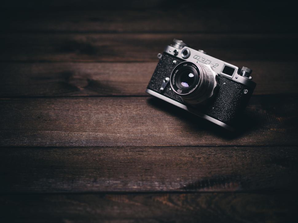 Free Image of Vintage camera on dark wooden surface, focused lens 