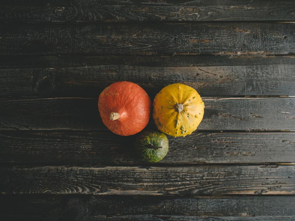 Free Image of Three colorful pumpkins on dark wooden background 