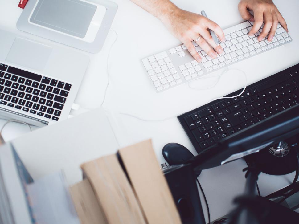 Free Image of Hands typing on multiple keyboards in an office setup. 