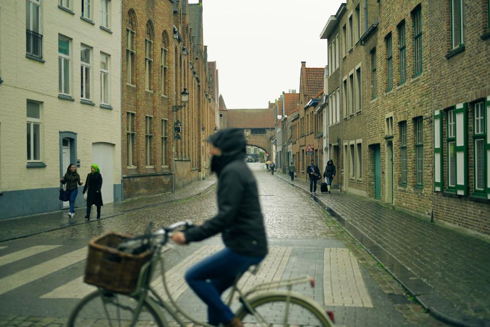 Free Image of Person riding bike on cobblestone street, blurred motion 