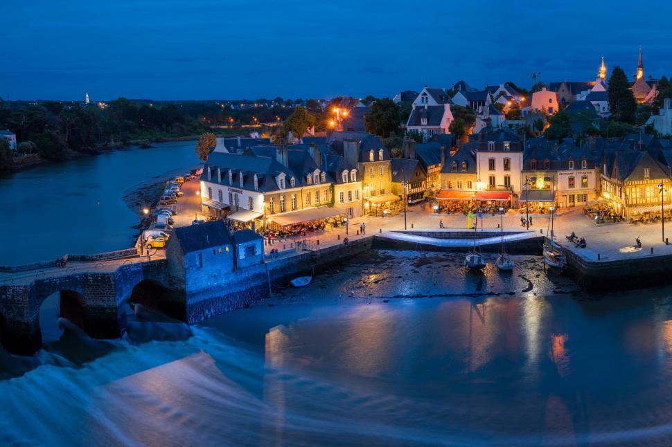 Free Image of Nightfall in a quaint riverside village with lights on 