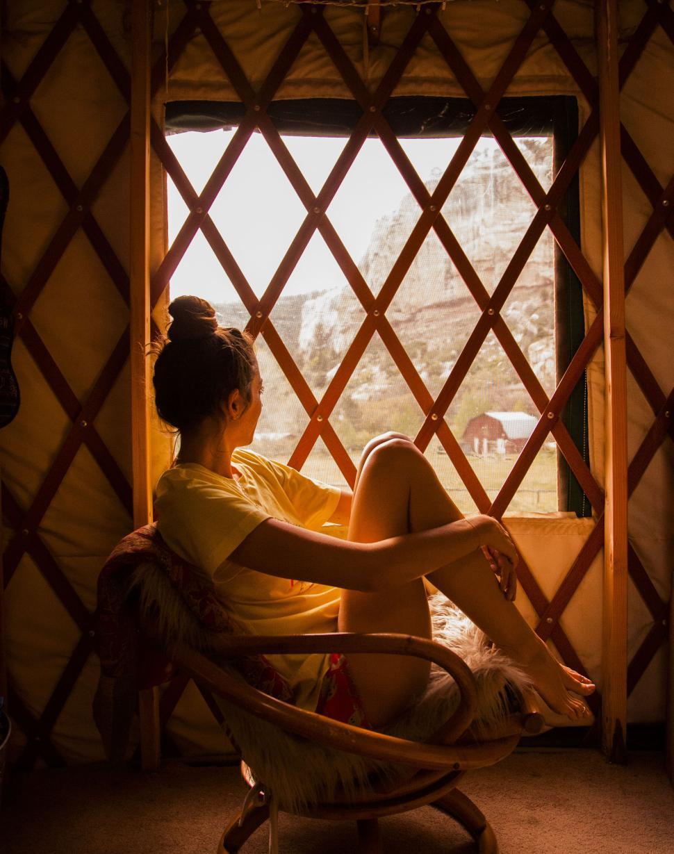 Free Image of Woman in yurt looking at mountain through window 