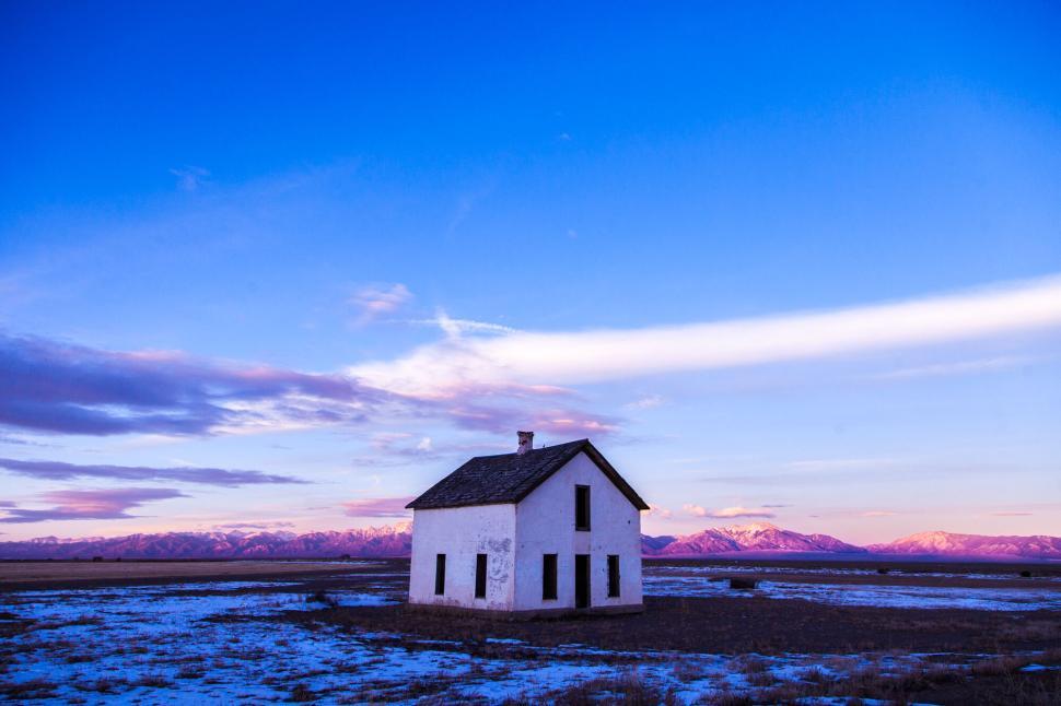 Free Image of White house on open field with mountain and blue sky 