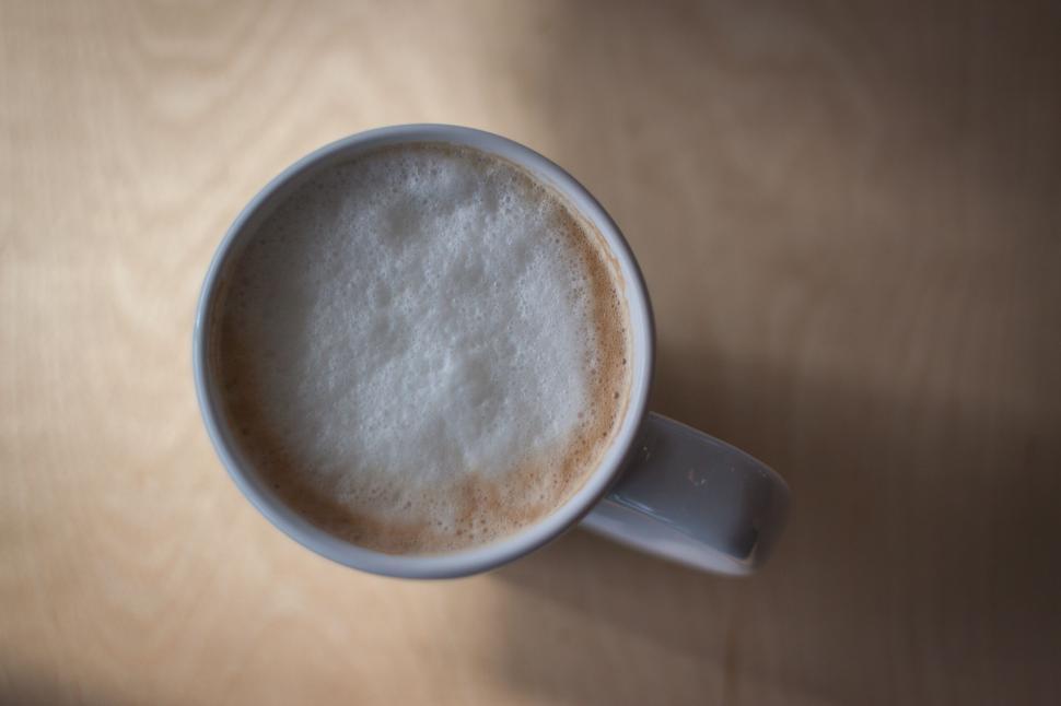 Free Image of Steaming cup of coffee on a wooden table top view. 