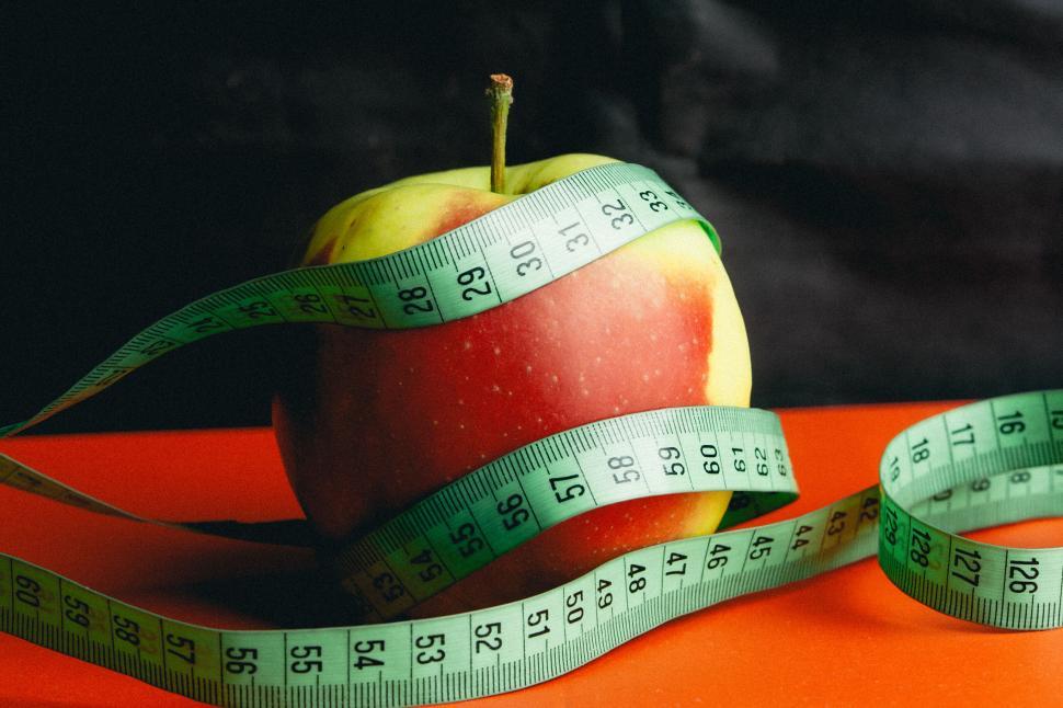 Free Image of Apple with green measuring tape coiled around it. 