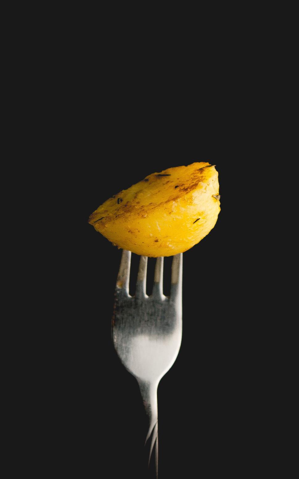 Free Image of A single roasted potato wedge on a fork isolated. 