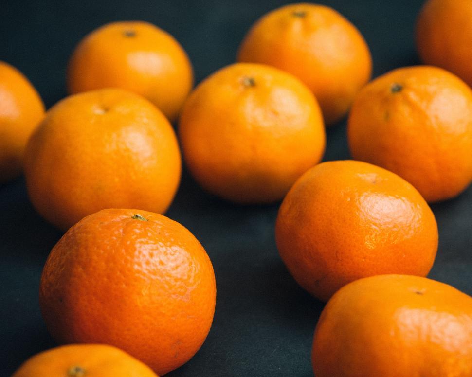 Free Image of Pile of fresh oranges arranged on a dark surface. 
