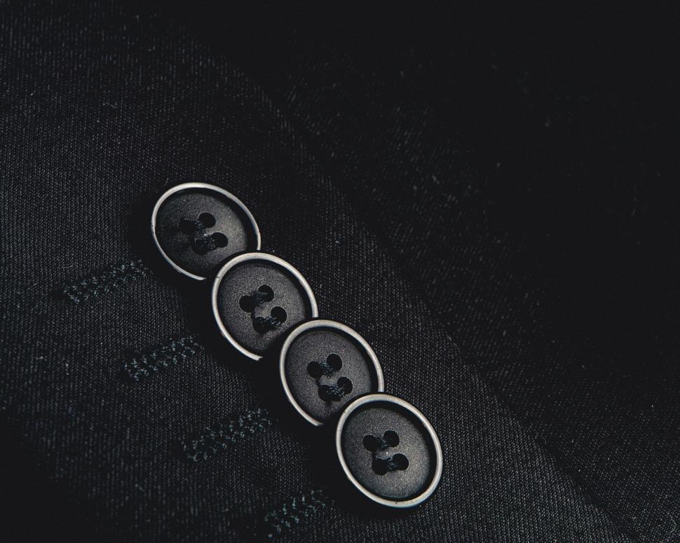 Free Image of Four black buttons on dark fabric in close-up view. 