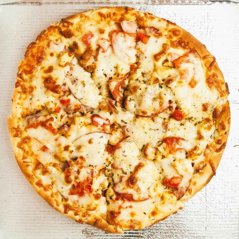 Free Image of Freshly baked pizza with cheese, tomatoes, and herbs. 