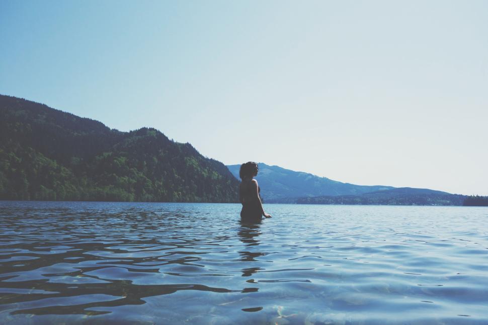 Free Image of Individual standing in a serene lake surrounded by beauty. 