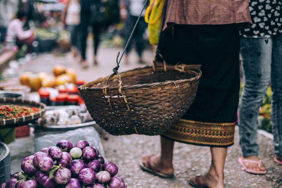 Free Image of Market vendor with basket standing near vegetables. 