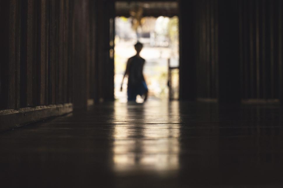 Free Image of Silhouette of a person walking down a dimly lit hallway 