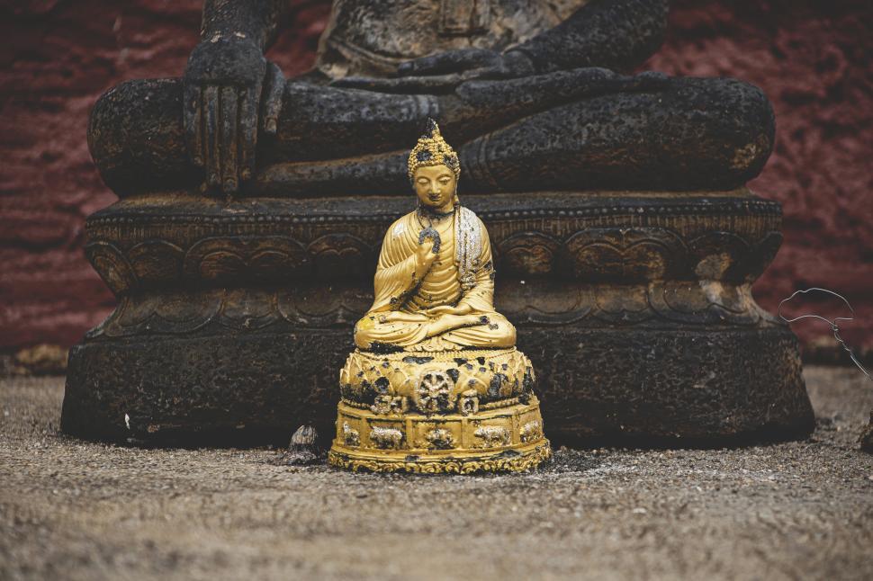 Free Image of Small golden Buddha statue in front of larger statue 