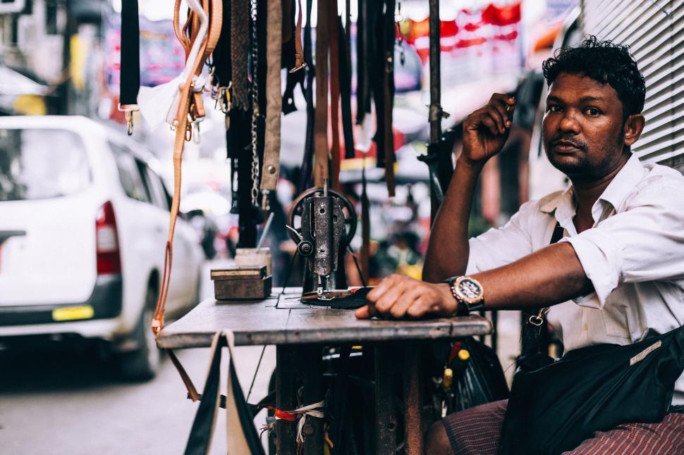 Free Image of Man working at a sewing machine on a busy street, serious 