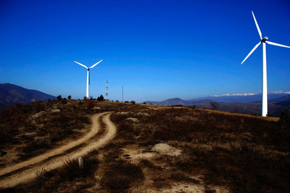 Free Image of Wind turbines on a hill under a clear blue sky. 