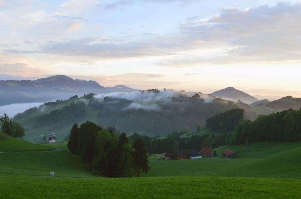 Free Image of Scenic view of fog-covered hills at dawn with greenery. 