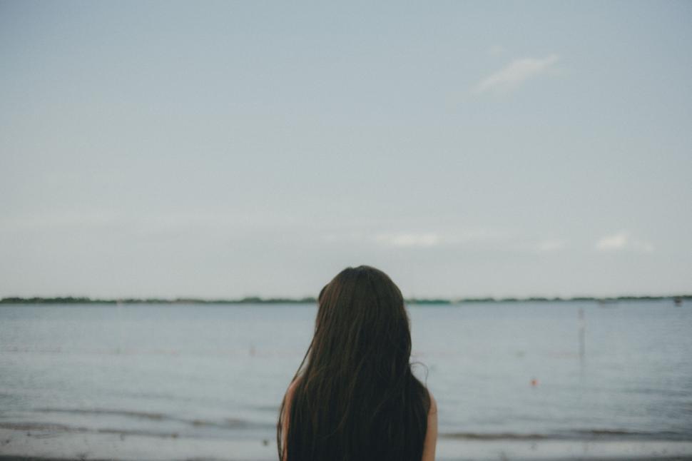 Free Image of Individual gazing out over calm waters and coastline. 