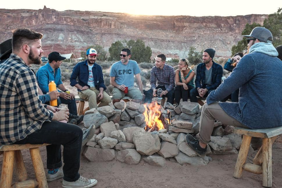 Free Image of Friends sitting around campfire in scenic outdoor setting 