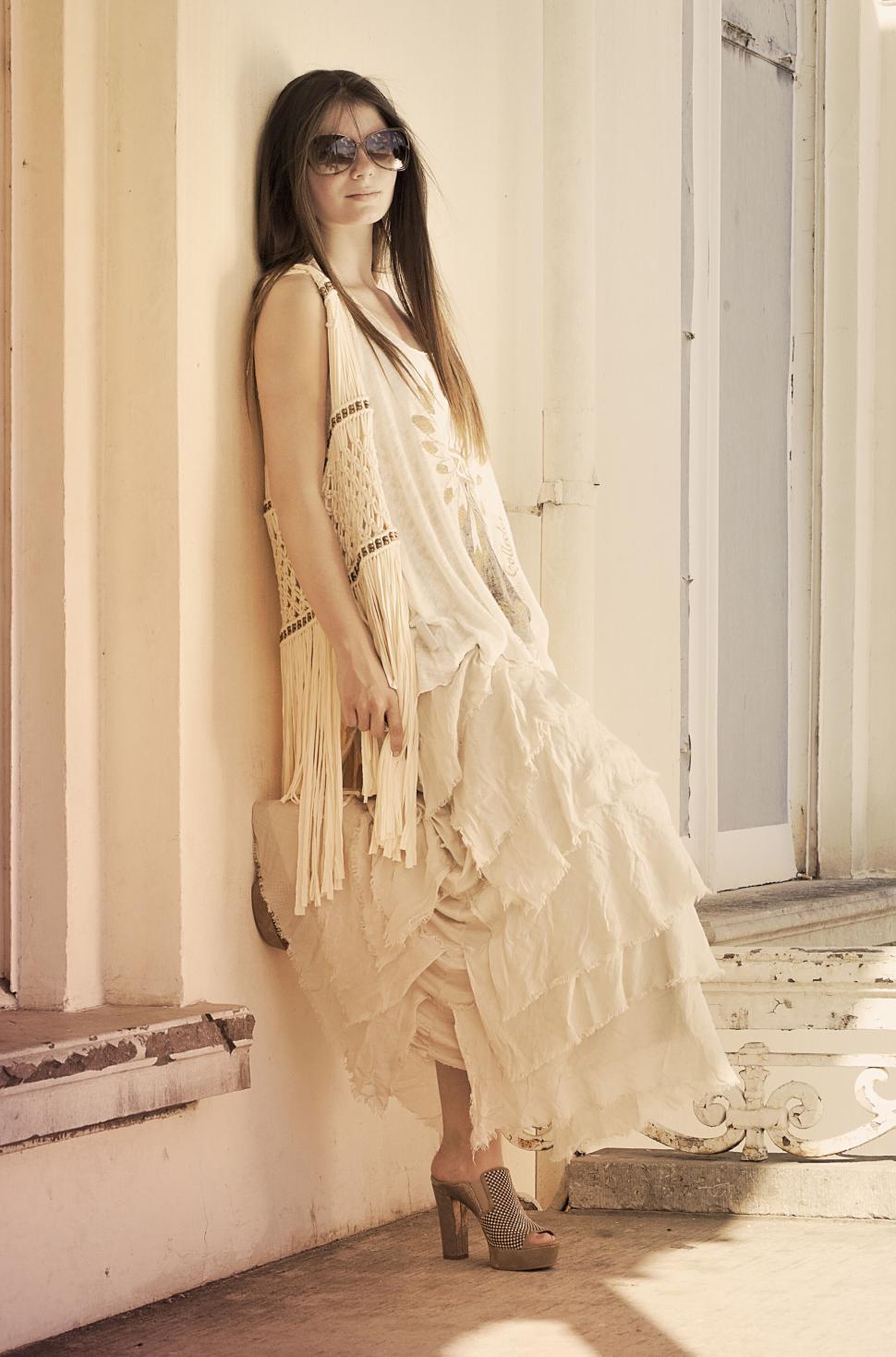 Free Image of Pose in boho dress by a carved pillar with calm expression 