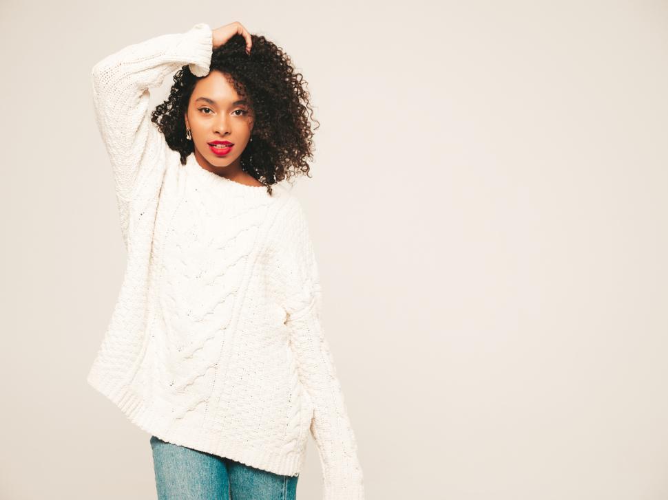 Free Image of Woman in white sweater with hand in hair, posing 