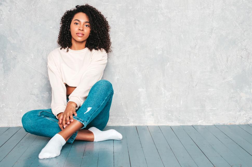 Free Image of Young woman sitting on floor wearing casual clothes 