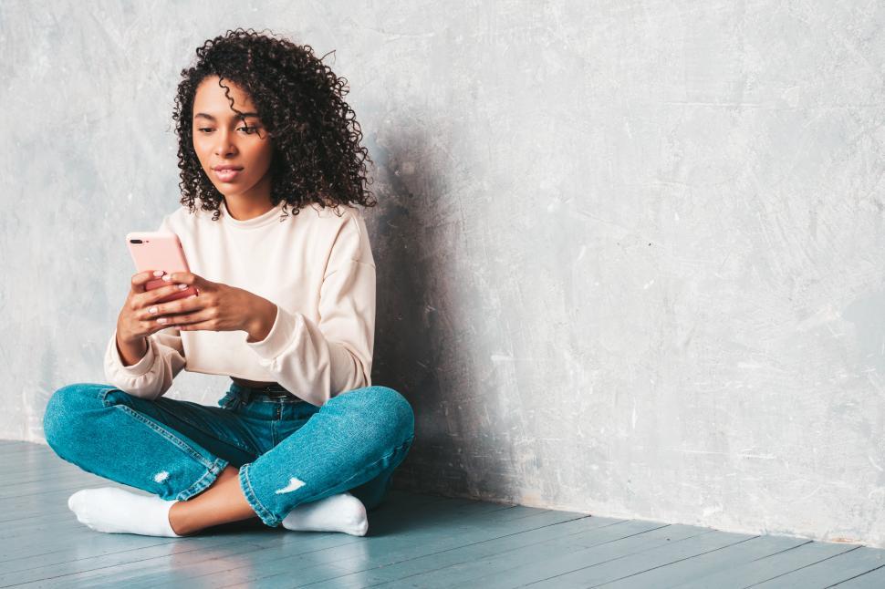 Free Image of Woman using smartphone while seated on floor indoors 