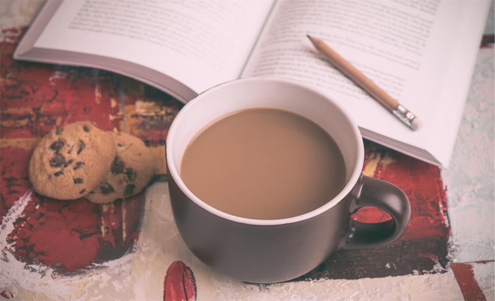 Free Image of Cup of coffee and cookies next to an open book, cozy setup 