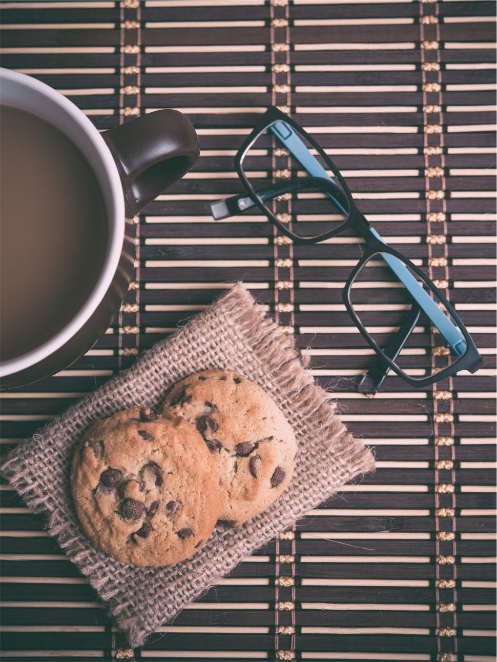Free Image of Cup of coffee, cookies, glasses on a textured mat 
